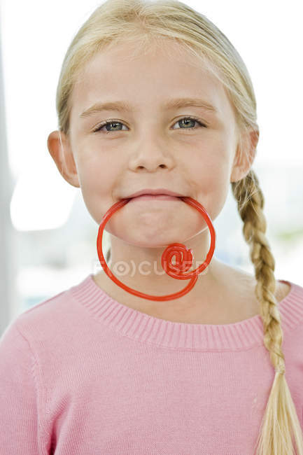 Portrait of little girl holding candy in mouth — Stock Photo