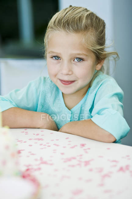 Портрет улыбающейся девочки, сидящей за столом — стоковое фото