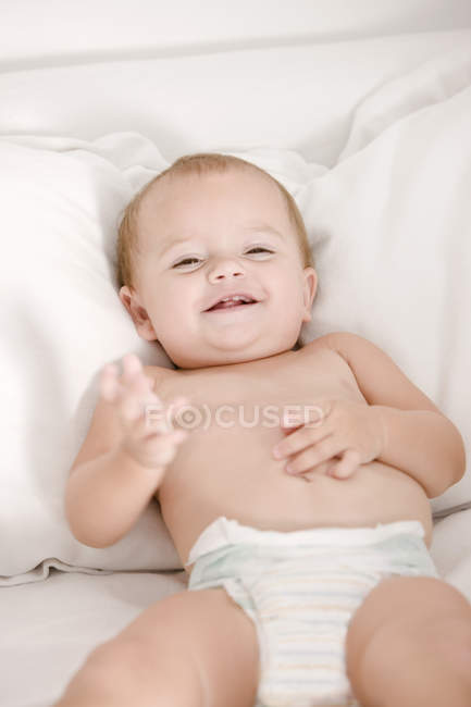 Primo piano di carina bambina sdraiata sul letto e sorridente — Foto stock