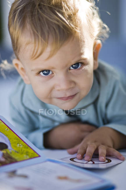 Ritratto del bambino che legge il libro illustrativo e guarda la macchina fotografica — Foto stock