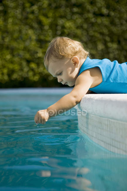 Baby boy playing with water in swimming pool — Stock Photo