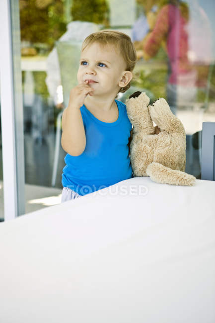 Малыш держит плюшевого мишку и смотрит вверх — стоковое фото