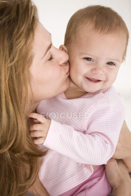 Nahaufnahme einer glücklichen Frau, die ihre kleine Tochter küsst — Stockfoto