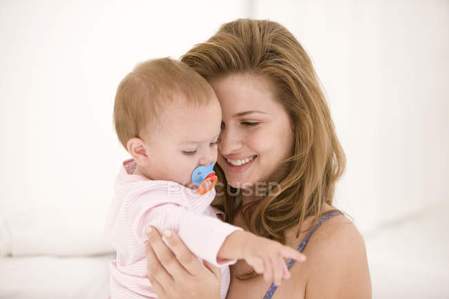 Smiling woman carrying baby daughter — Stock Photo