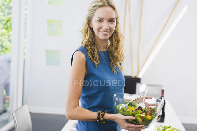 Портрет молодой женщины, держащей миску салата дома — стоковое фото