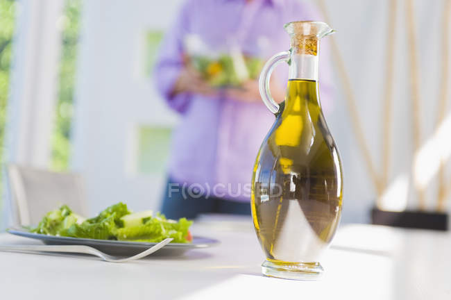 Salad oil with plate of salad on dining table — Stock Photo