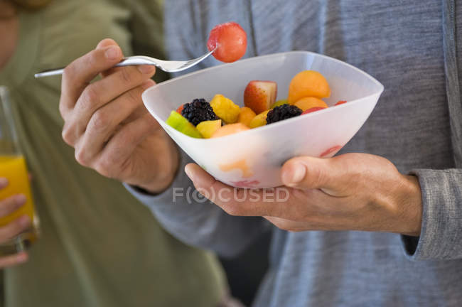 Gros plan des mains masculines tenant un bol de salade de fruits — Photo de stock