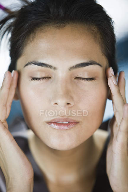 Close-up of brunette woman rubbing temples — Stock Photo