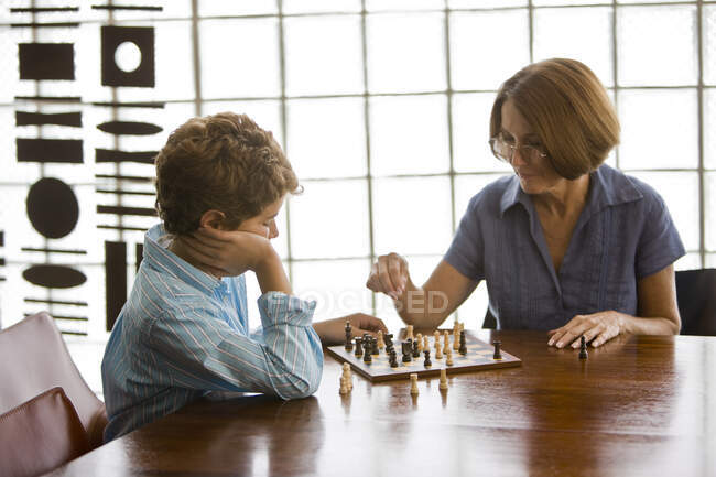 Женщина играет в шахматы со своим внуком — стоковое фото