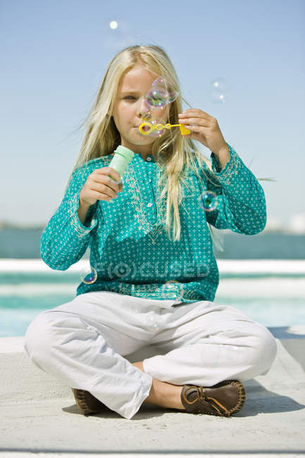 Mädchen pustet Seifenblasen mit Blasenstab am Strand — Stockfoto