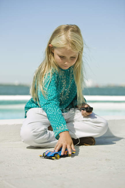 Chica jugando con el coche de control remoto en la playa de arena - foto de stock