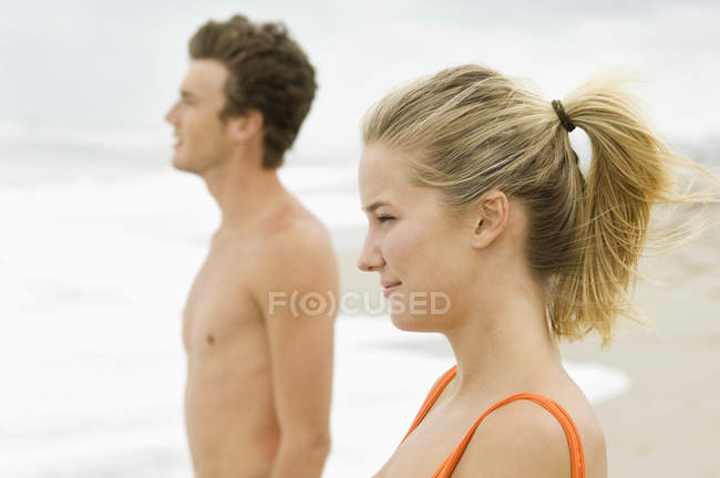 Primer plano de la pareja de pie en la playa y mirando a la vista - foto de stock