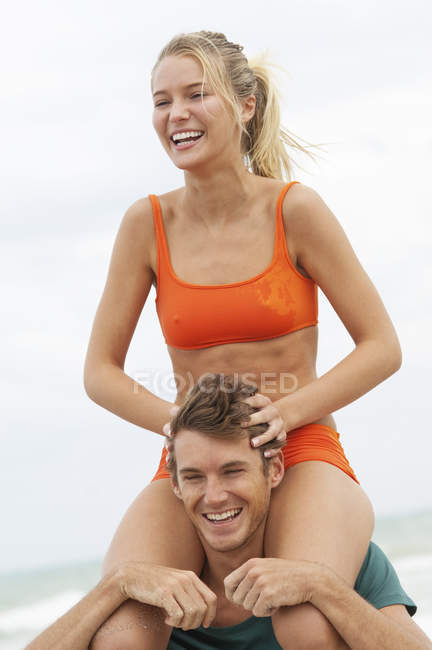 Man carrying woman on shoulders on beach — Stock Photo