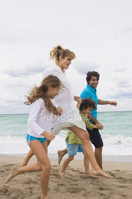 Щаслива сім'я біжить на піщаному пляжі — стокове фото