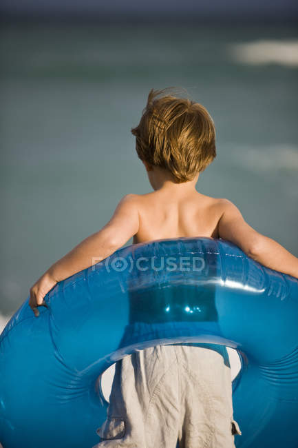 Menino carregando anel inflável na praia — Fotografia de Stock