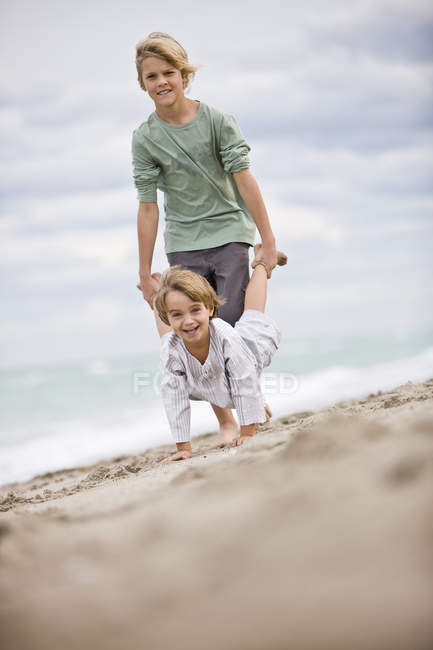Веселі хлопчики грають на піщаному пляжі — стокове фото