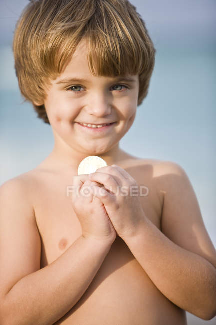 Portrait de petit garçon torse nu souriant tenant pièce de monnaie — Photo de stock