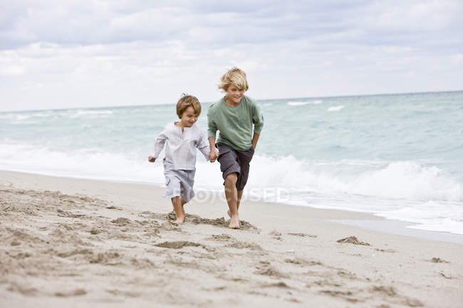 Веселые мальчики бегают по песчаному пляжу — стоковое фото