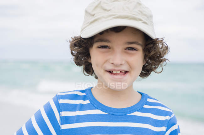 Портрет улыбающегося мальчика в кепке на пляже — стоковое фото