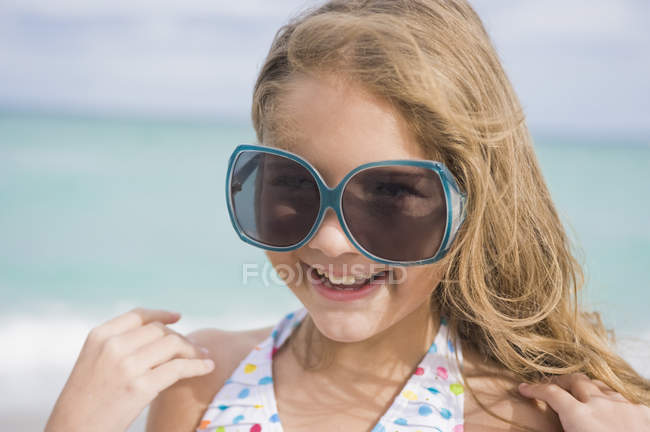 Портрет усміхненої дівчини у великих сонцезахисних окулярах на пляжі — стокове фото