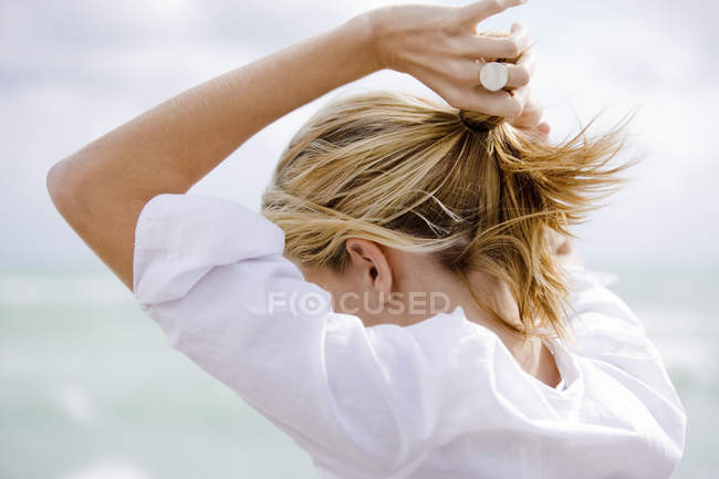 Femme blonde mettant les cheveux en queue de cheval à l'extérieur — Photo de stock