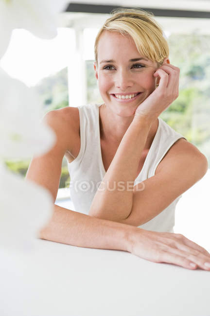 Крупный план белокурой улыбающейся женщины, которая смотрит в сторону — стоковое фото