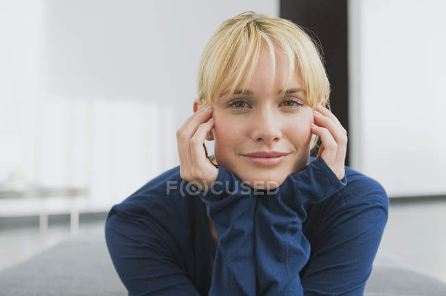 Retrato de mujer joven con la cabeza en las manos mirando a la cámara - foto de stock
