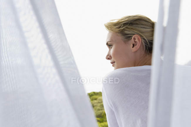 Vista posteriore della donna in piedi sul balcone e guardando la vista — Foto stock