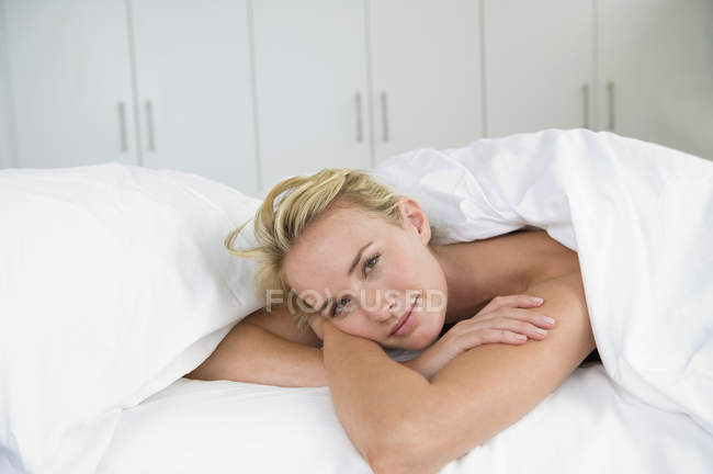 Портрет чувственной молодой женщины, лежащей на кровати — стоковое фото