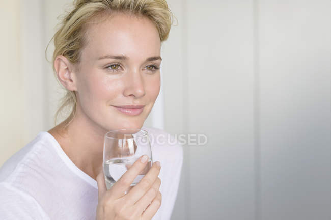 Sorrindo mulher sonhadora segurando vidro de água — Fotografia de Stock