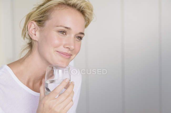 Smiling woman holding glass of water — Stock Photo