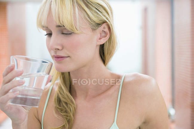 Jeune femme blonde tenant un verre d'eau — Photo de stock