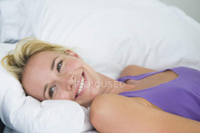 Смеющаяся молодая женщина лежит на кровати и улыбается — стоковое фото