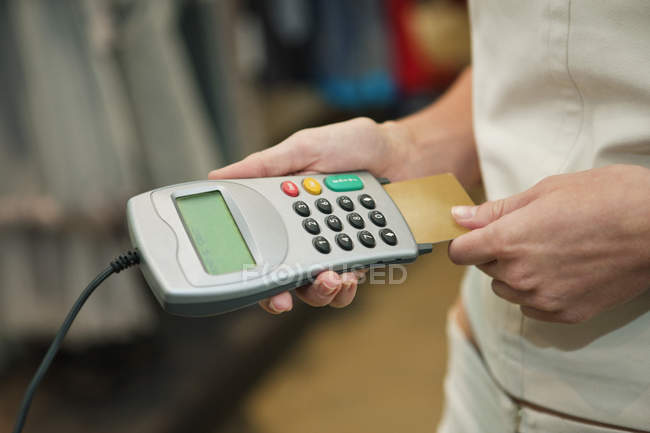 Primer plano del cliente utilizando el lector de tarjetas de crédito en la boutique - foto de stock