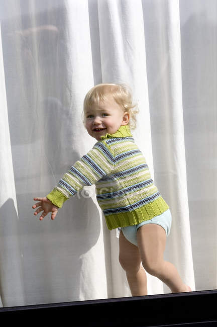 Allegro bambino in piedi dietro la finestra — Foto stock