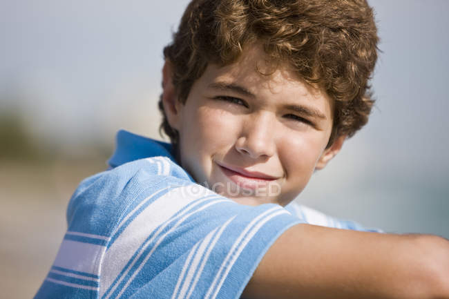Портрет усміхненого хлопчика, що сидить на пляжі — стокове фото