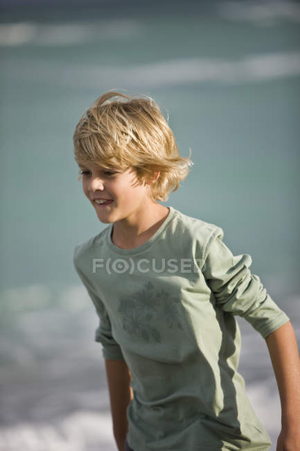 Niño sonriente caminando en la playa - foto de stock