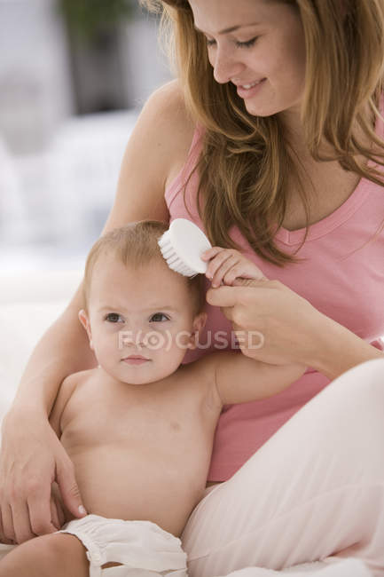 Femme brossage bébé fille cheveux — Photo de stock