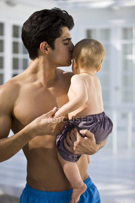Sem camisa jovem homem beijando bebê filho — Fotografia de Stock