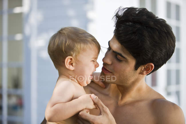 Closeup of young man consoling crying son — Stock Photo