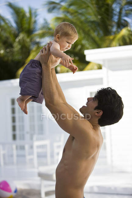 Веселий чоловік збирає маленького сина на відкритому повітрі — стокове фото