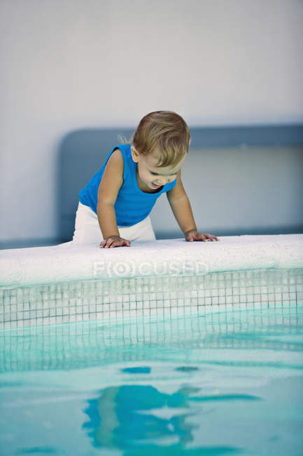 Cute baby boy looking into swimming pool — Stock Photo