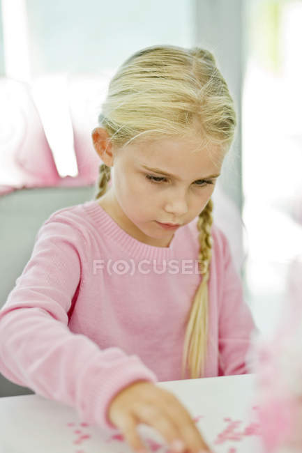 Зосереджена блондинка маленька дівчинка сидить на стільці і займається мистецтвом — стокове фото