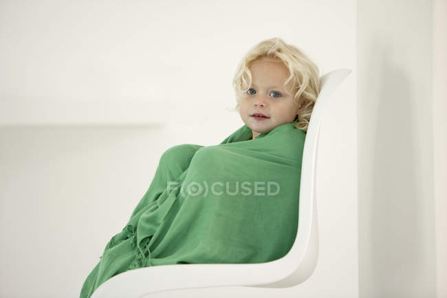 Retrato de menina bonito envolto em xale verde sentado na cadeira — Fotografia de Stock