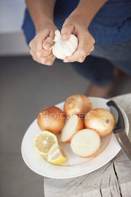 Крупный план женских рук, очищающих овощи в тарелке — стоковое фото