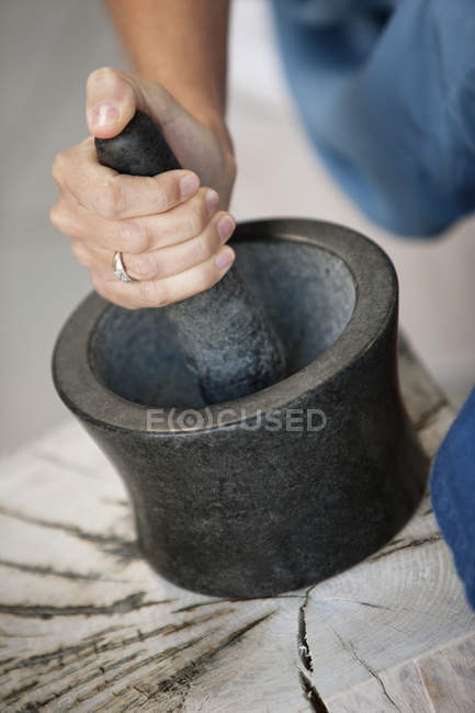 Gros plan de la main féminine à l'aide de mortier et pilon — Photo de stock
