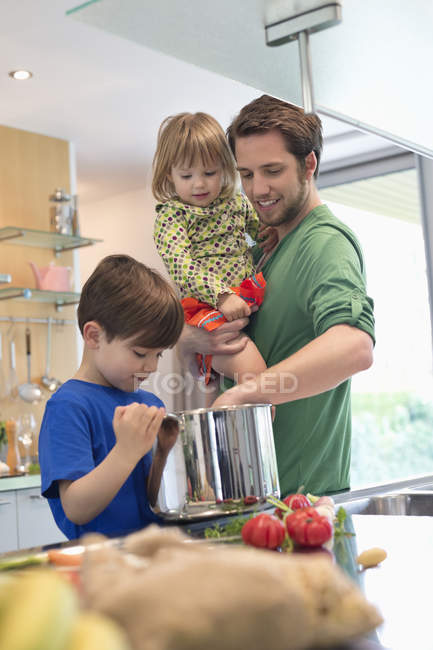 Man with son and daughter cooking in kitchen — Stock Photo