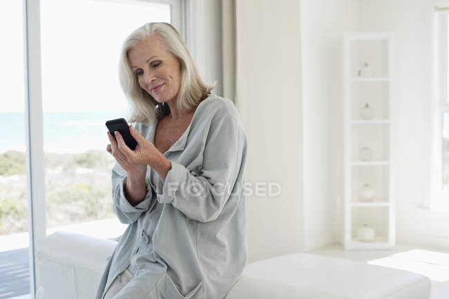 Lächelnde Frau benutzt Handy in Haus an der Küste — Stockfoto