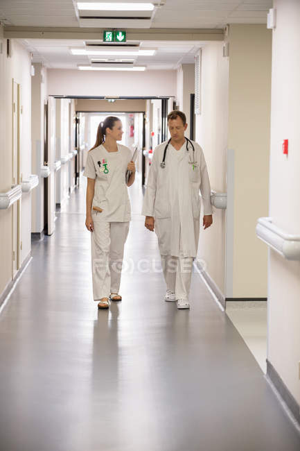 Médico e enfermeira andando no corredor de um hospital — Fotografia de Stock