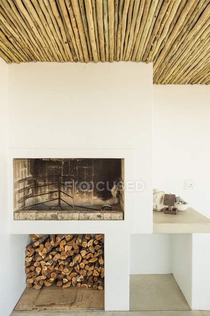 Cheminée avec bois de chauffage sous toit en bambou — Photo de stock